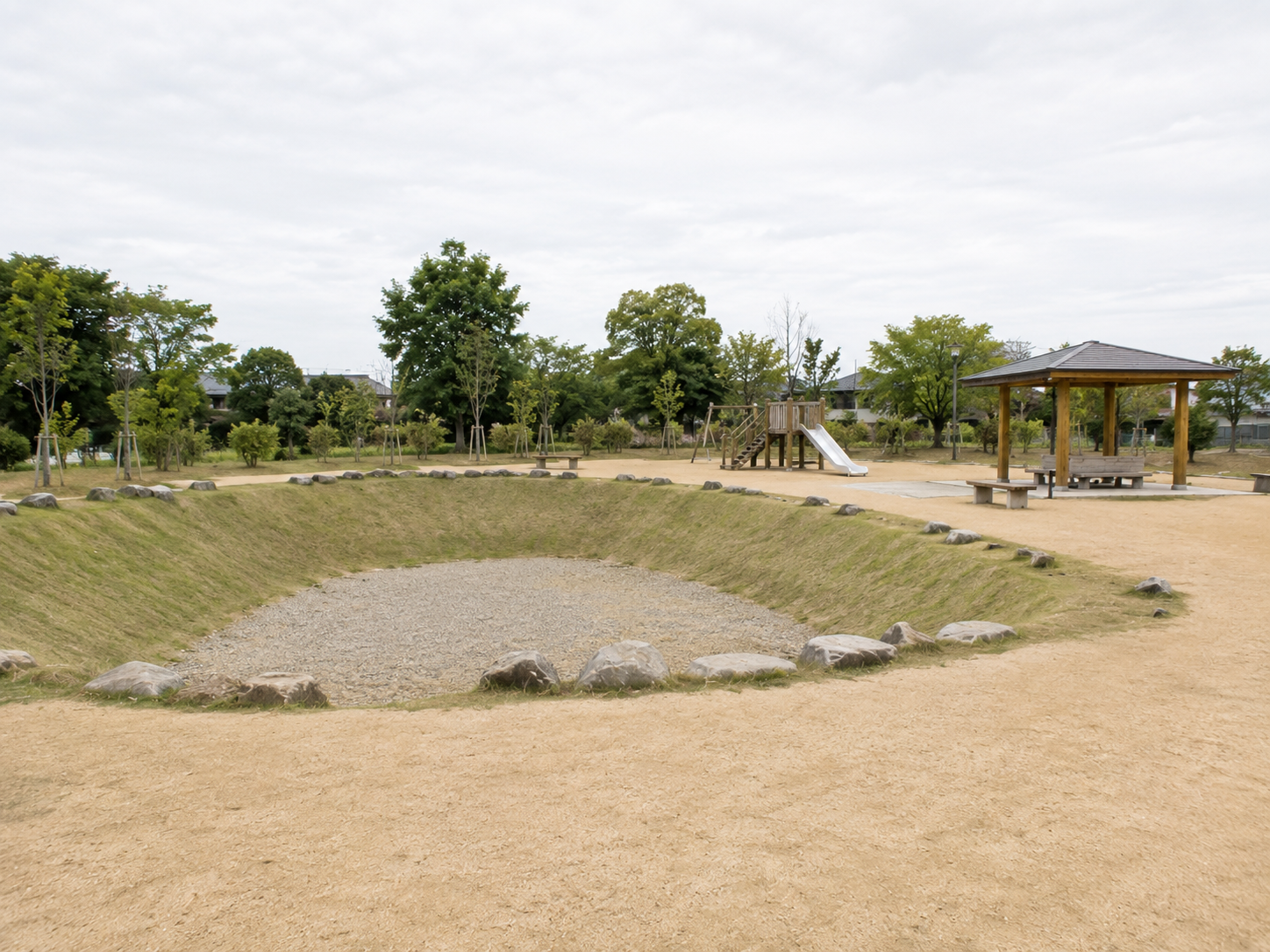 調整池を兼ねた地域の公園。広場と遊具、芝で覆われたくぼ地